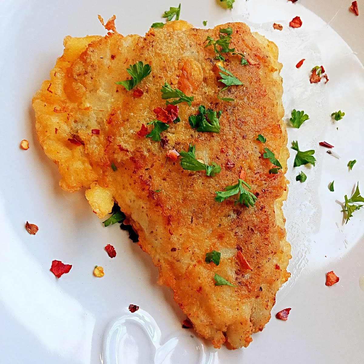 Crispy golden-brown fish fillet made with HEBA gluten-free, low-carb batter. Perfectly pan-fried and garnished with parsley and chili flakes.